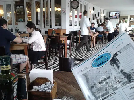 Salão de bar com mesas, garçons e cardápio Boteco